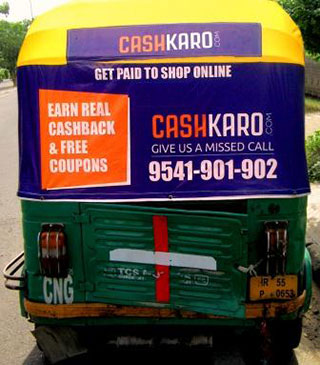 Backside of an auto standing on the road that has an auto rickshaw advertisement of Cashkaro app